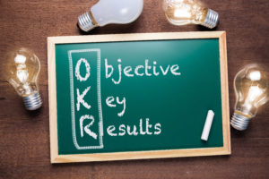 OKR or Objective Key Results acronym text on chalkboard with many glowing light bulbs, washington dc, crosslead